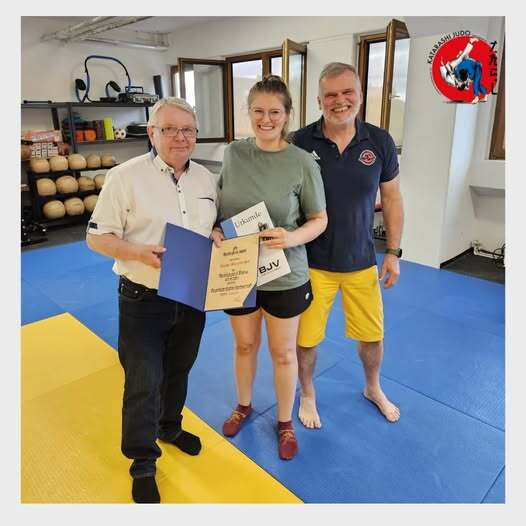 Verleihung_Bronze_Nadel_Leona Leona hält eine Urkunde in der Hand, rechts von ihr steht lothar stv.Vorsitzender des blsv Mittelfranken und links unser Abteilungsleiter Jochen